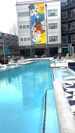A swimming pool with lounge chairs and a mural on the building behind. - Atlanta Beltline Luxury Suite (Atlanta)