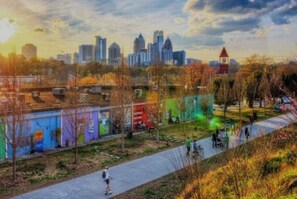 Une vue urbaine avec un espace vert comprenant un sentier, des arbres et un bâtiment orné de peintures murales colorées.
