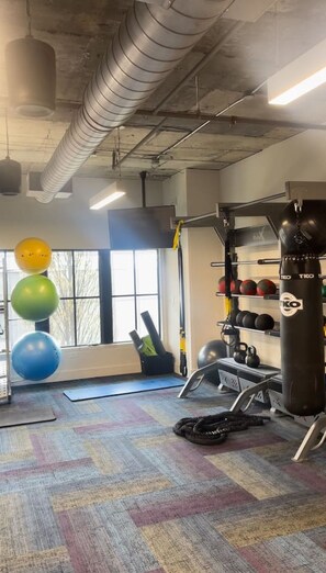 A gym with exercise equipment, a punching bag, and a window with natural light. - Atlanta Beltline Luxury Suite (Atlanta)