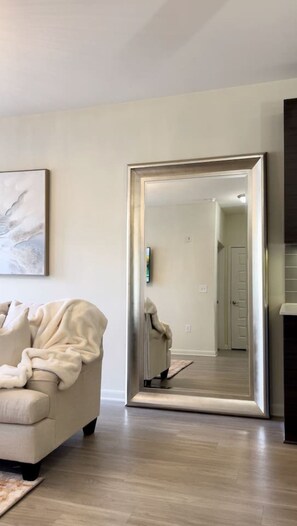 Un salon avec un grand miroir, un canapé et un plancher en bois.