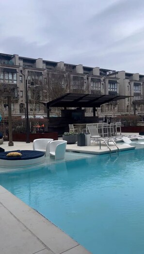A swimming pool with lounge chairs and a covered seating area.