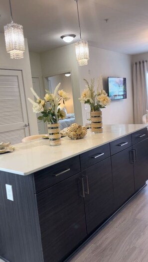 A modern kitchen with dark cabinetry, a marble countertop, and two hanging pendant lights.