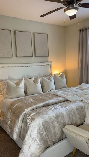 A bedroom with a bed, pillows, a chair, and a ceiling fan. - Atlanta Beltline Luxury Suite (Atlanta)