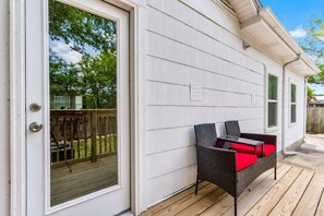 Eine überdachte Terrasse mit Korbmöbeln, ein Holzboden und eine weiße Außenwand.
