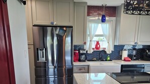 Una cocina moderna con electrodomésticos de acero inoxidable, encimera de granito y un original panel de madera.