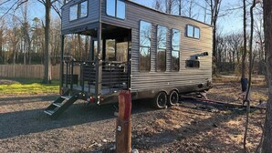 A mobile home with a covered porch, multiple windows, and a ramp leading to the entrance.