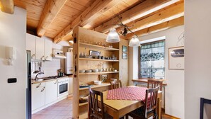 Una cocina con armarios de madera, una mesa de comedor con sillas y lámparas colgantes.