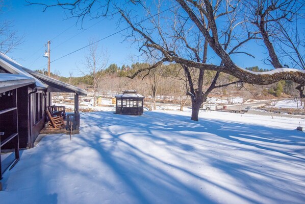A snow-covered outdoor area with a gazebo, a covered seating area, and a tree.