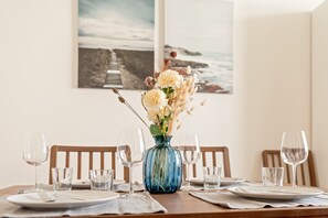 Et spisebord dækket med tallerkener, glas og en vase med blomster.