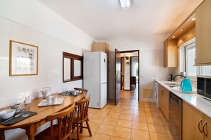 A kitchen with a dining table, chairs, a refrigerator, and a washing machine.
