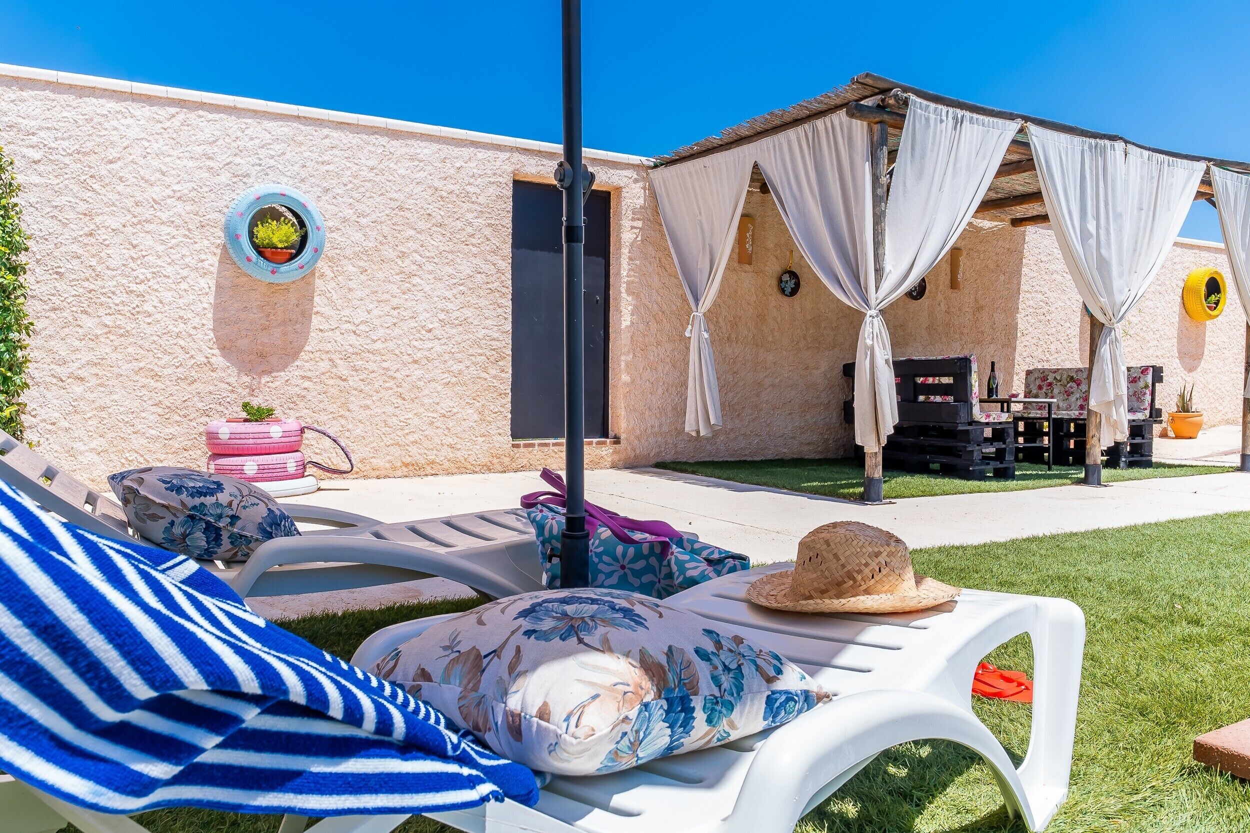 A patio area with lounge chairs, a table, and a covered seating area.