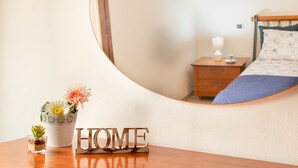 Une chambre à coucher avec un lit, une table de chevet, une lampe et un miroir qui reflète la pièce.