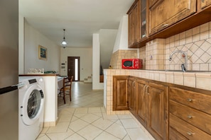 A kitchen with wooden cabinets, a microwave, and a washing machine.