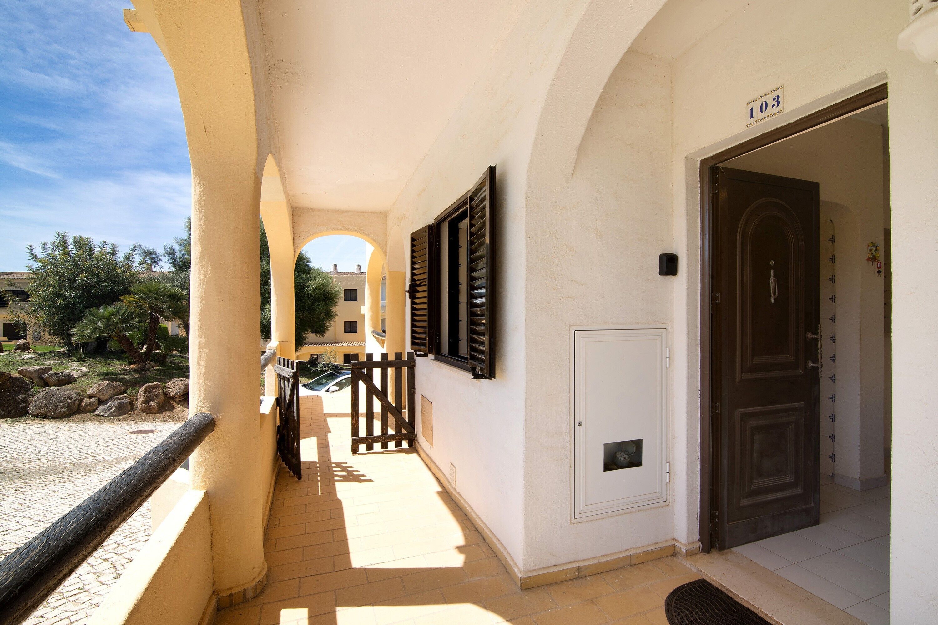 A corridor with a door marked '103,' a wooden gate, and a tiled floor.
