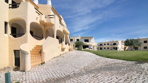 Un patio con suelo de adoquines, edificios con arcos y un cielo despejado.