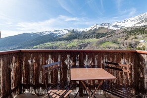 A balcony with a table and chairs, overlooking a mountainous landscape with snow-capped peaks. - Apartment 'Appartement St François Longchamp' with Mountain View and Balcony (Saint-François-Longchamp)