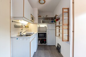 Een compacte keuken met een spoelbak, magnetron en een ingebouwde oven.