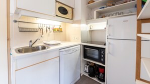 Una cocina compacta equipada con lavavajillas, microondas, horno y un refrigerador Haier.