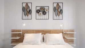 A modern bedroom with a wooden slatted headboard, white bedding, and three wall-mounted artworks. - Apartment 'Experiencia Marina A107' with Sea View, Wi-Fi and Air Conditioning (Torrox)