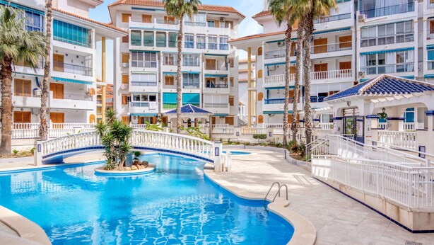 Un hôtel doté d’une piscine, de plusieurs balcons et de palmiers.