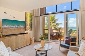 A spacious living room with a large flat-screen TV, a wooden cabinet, a round coffee table, and a comfortable seating area.