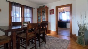 Un coin repas avec une table et des chaises en bois, un tapis à motifs et un meuble avec des portes en verre.