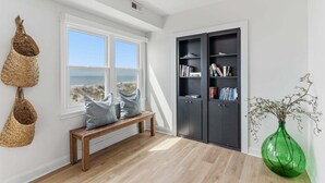 Ein Zimmer mit einer Holzbank, einem Bücherregal, einer grünen Vase und einem Fenster mit Blick.