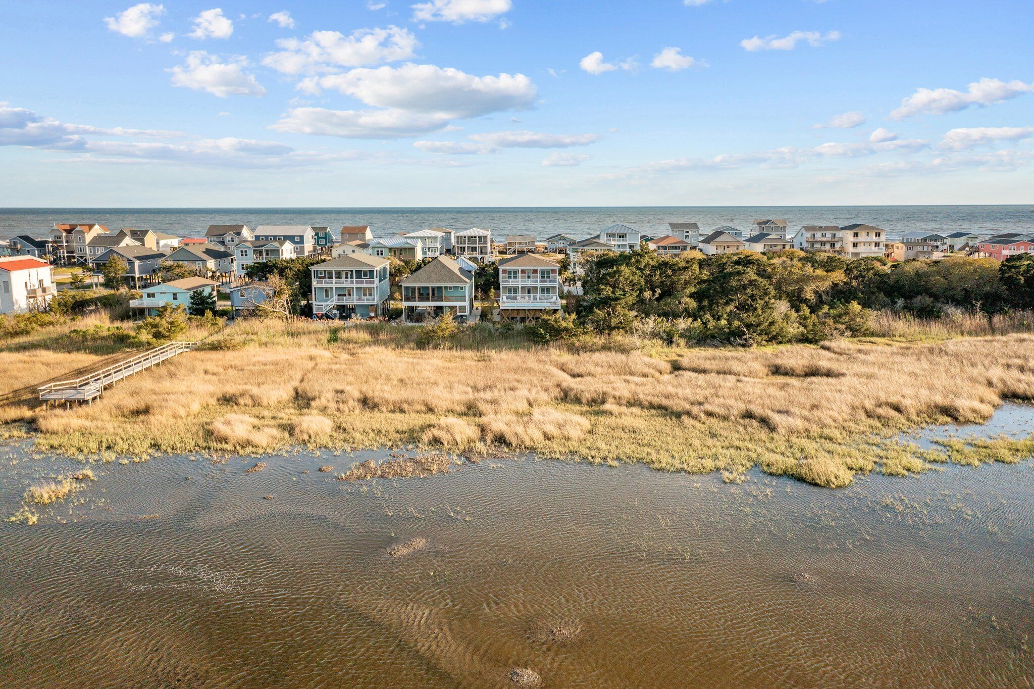 A coastal residential area with houses and a boardwalk leading to the water.