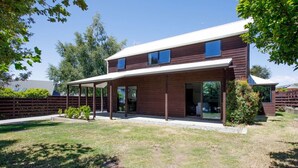 A modern two-story house with a covered patio, a fenced yard, and a well-maintained lawn. - Kings Little Secret four bedroom family home (Wānaka)