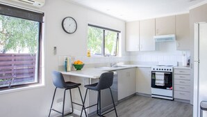 A modern kitchen with a built-in oven, a sink, and two bar stools. - Kings Little Secret four bedroom family home (Wānaka)