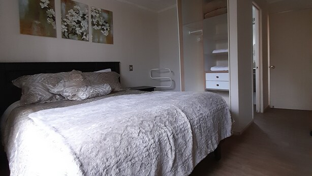 Un dormitorio con cama, armario y puerta que da a otra habitación.