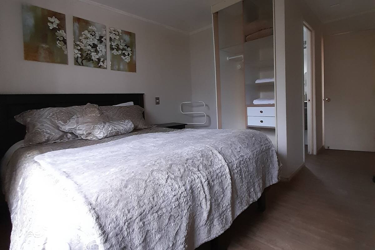 Ein Schlafzimmer mit einem Bett, einem Kleiderschrank und einer Tür zu einem anderen Raum.