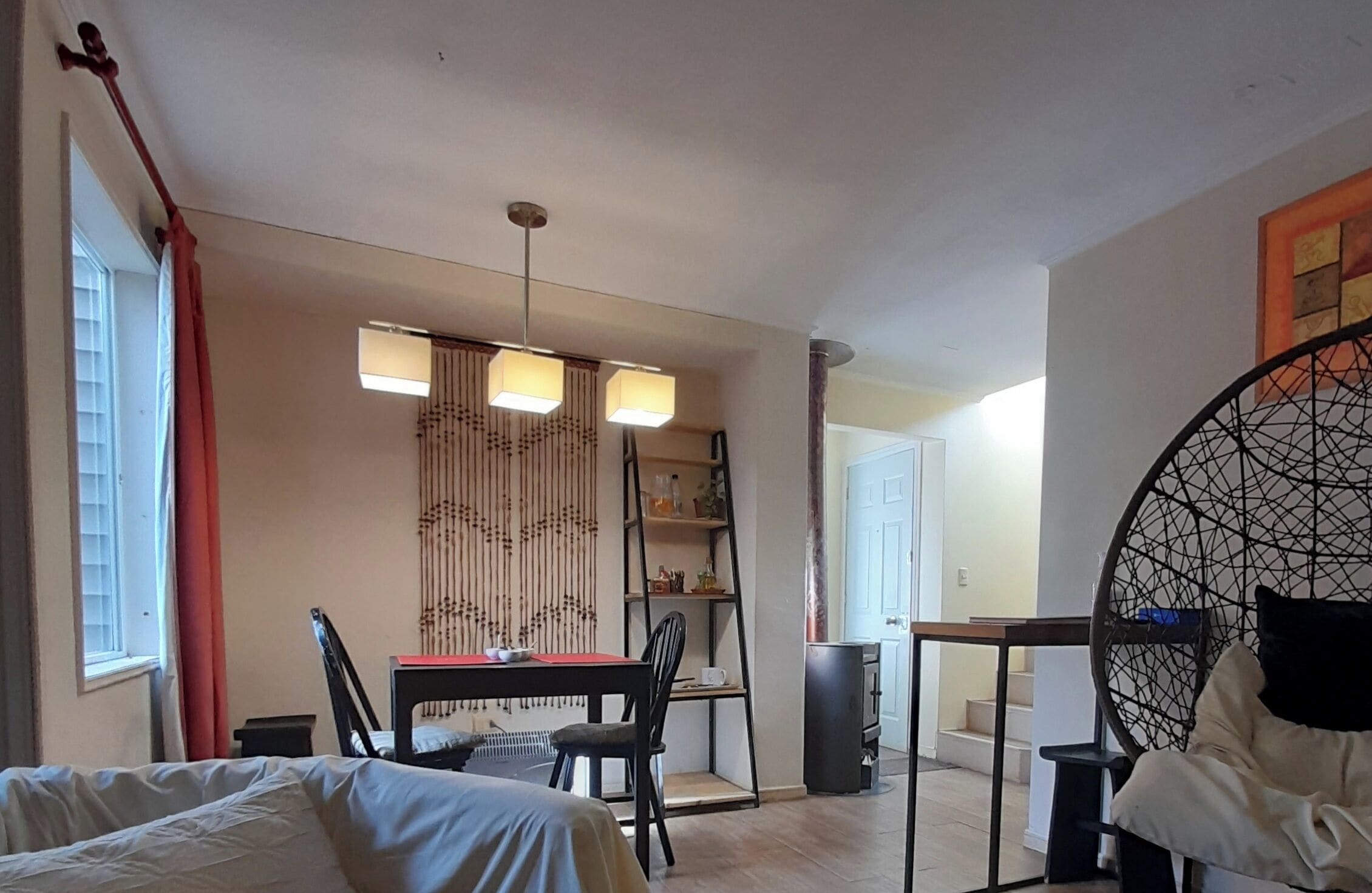 A compact room with a bed, a dining table with chairs, a small kitchen area, and a decorative wall panel.