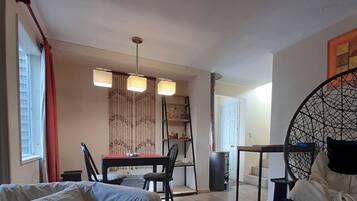A compact room with a bed, a dining table with chairs, a small kitchen area, and a decorative wall panel.