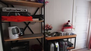 Una habitación compacta con un estante de madera que contiene diversos objetos, como una tetera, una maleta y adornos.