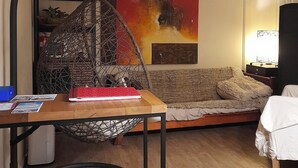Un salón acogedor con una mesa de madera, una silla colgante, un sofá y una cama.