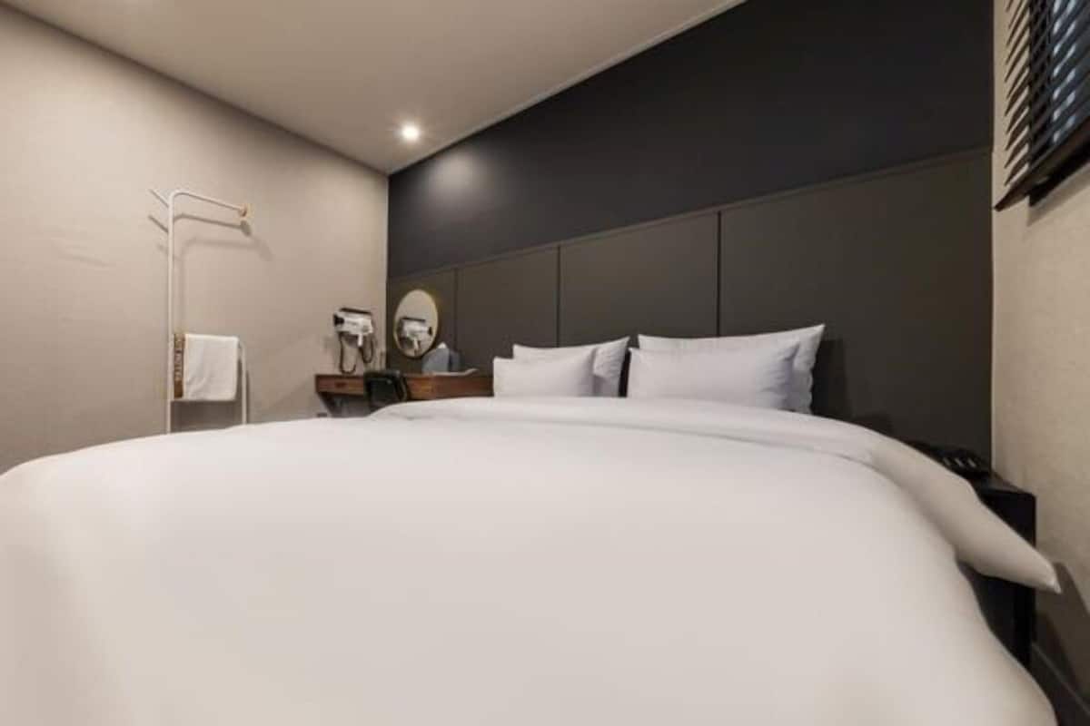 Een moderne hotelkamer met een groot bed, een nachtkastje met een lamp en een spiegel.