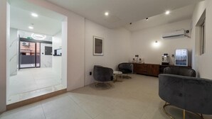 Un hall d’hôtel moderne avec un comptoir d’accueil, un espace salon et une grande fenêtre.