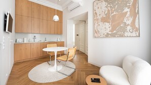 A modern kitchen with wooden cabinets, a dining table with chairs, and a large abstract painting on the wall. - Piękna Chic Apartment (Warszawa)