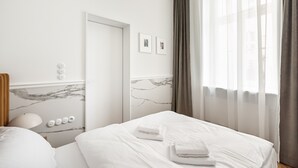 A hotel room with a bed, a nightstand, a mirror, and a window with curtains. - Piękna Chic Apartment (Warszawa)