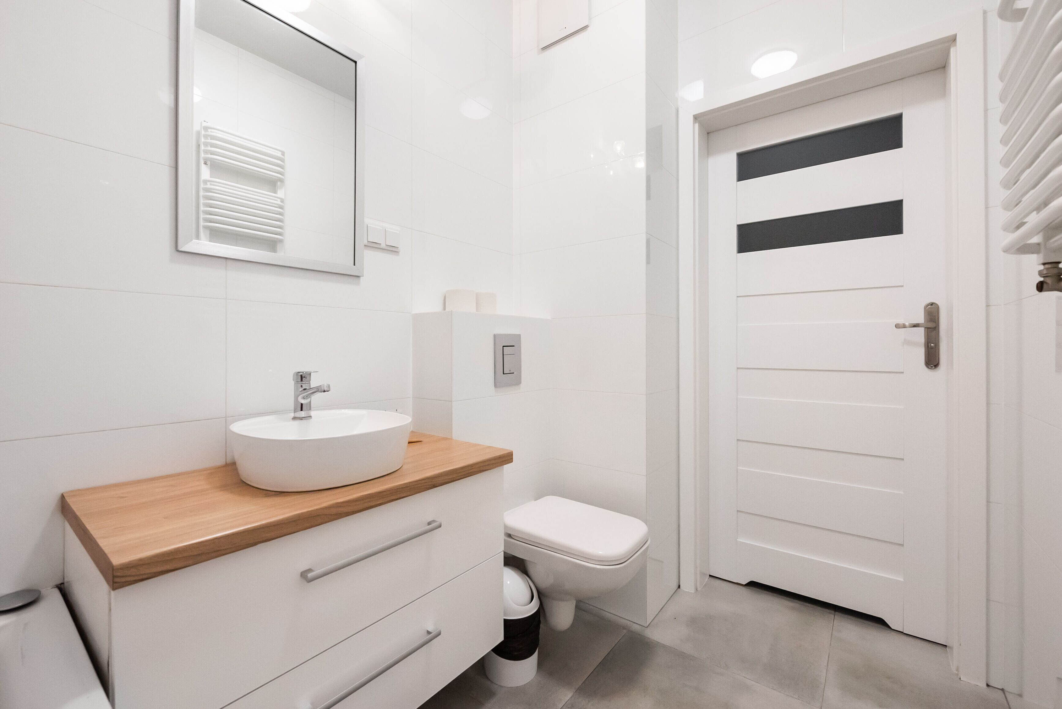 A modern bathroom with a white sink, wooden countertop, and a toilet.