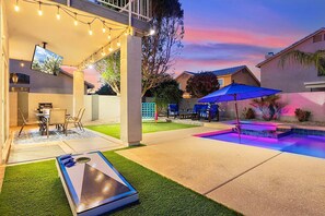 A backyard with a pool, outdoor seating, and string lights.