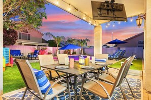 Una terrazza all'aperto con tavolo, sedie, luci decorative a tenda e ombrelloni.