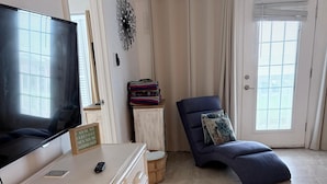 Un salon avec un téléviseur, un canapé, un meuble et une porte avec des rideaux.