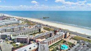 Un hôtel situé sur la côte, composé de plusieurs bâtiments, avec une plage et une jetée.