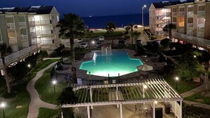 Un espace piscine offrant une vue dégagée sur l’océan, entouré d’immeubles à plusieurs étages dotés de balcons.