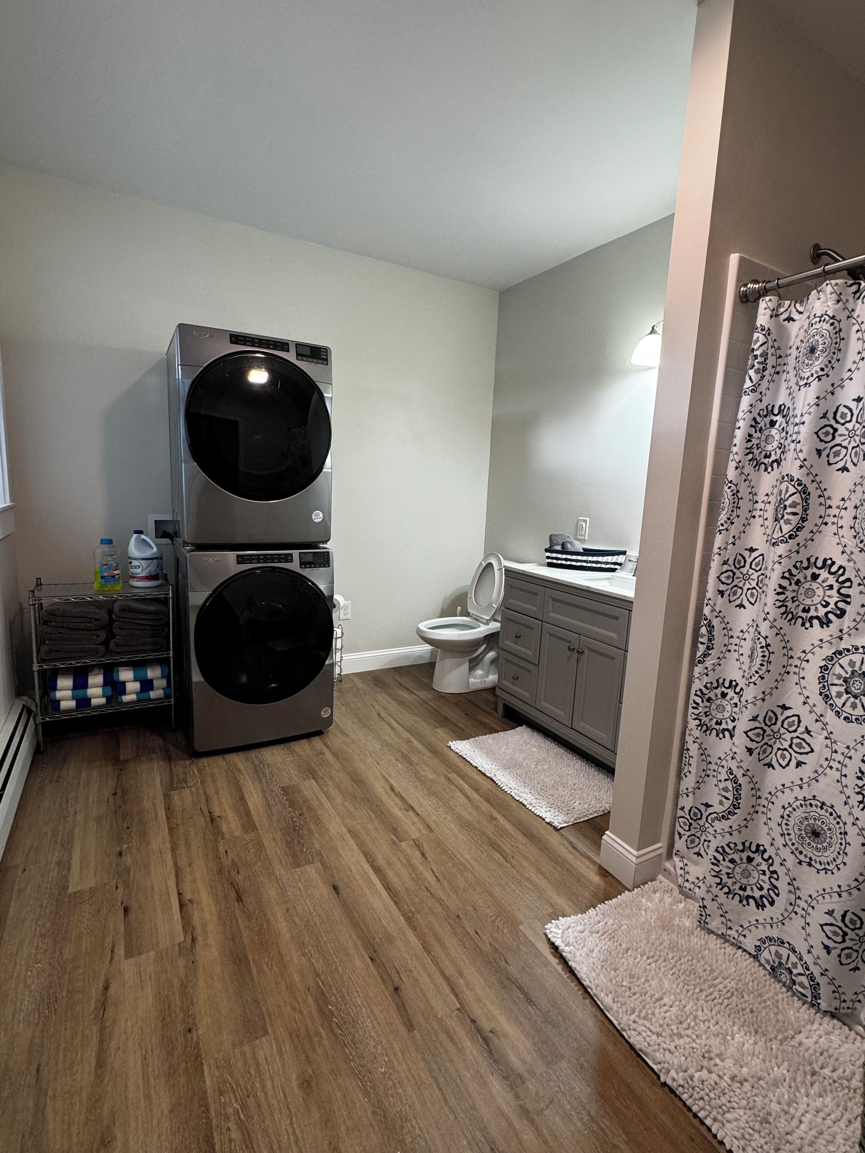 A compact bathroom with a double washer-dryer unit, a toilet, and a shower area.