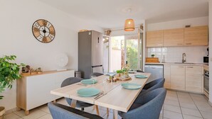 A modern kitchen with wooden cabinets, a built-in oven, and a dining area with a wooden table and blue chairs. - Cosy apartment for 6 people with WIFI, A/C, pool, TV and patio (Fréjus)