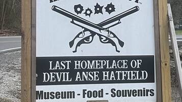 A signboard for Hatfield & McCoy, mentioning it as the last home of Devil Anse Hatfield, with sections for a museum, food, and souvenirs.