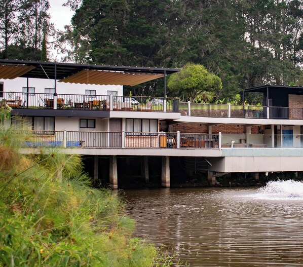 A modern multi-story house with a balcony overlooking a body of water.